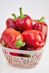 Image with a plastic container with a carved pattern filled with sweet bell peppers on a fabric...
