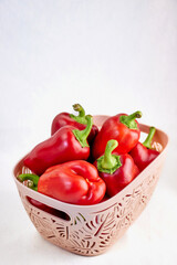 Image with a plastic container with a carved pattern filled with sweet bell peppers on a fabric background, space for text