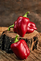 Still life of three sweet bell peppers lying on a wooden stump, concept of merging with nature,...