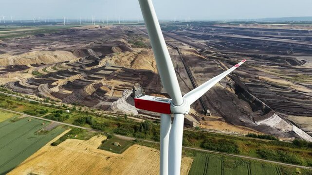Wind turbines in front of open pit lignite mine, aerial drone video. Renewable energy, mining fossil fuels.