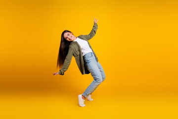 Cheerful young woman in casual outfit gesturing energetically on yellow background showcasing...