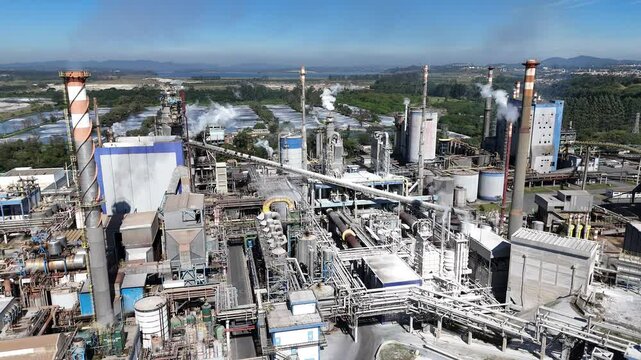 Aerial view of a paper production plant with prominent chimneys and boilers. The image illustrates industrial processes and the infrastructure of an operating paper factory