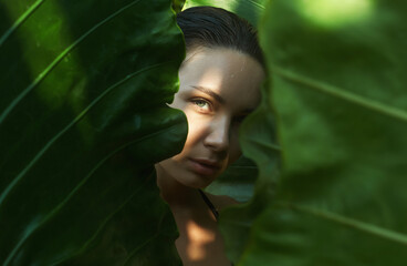 beautiful summer girl in palm leaves. young wet woman under palm tree in jungle
