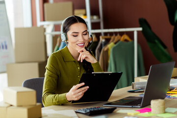 Young female entrepreneur working in a modern atelier workspace using laptop and documents,...