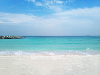 The beauty of the folds of the waves and the unique nature. A stunning beach view in the United Arab Emirates, where soft white sand stretches along the serene shoreline, meeting the calm.