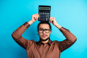 Young male professional holding a calculator in a playful pose against a vibrant teal background...