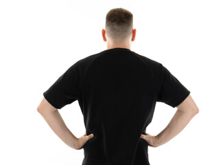 Person in black shirt stands with hands on hips, facing away from the camera against a white...