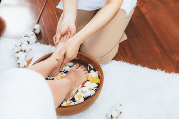Woman indulges in blissful foot massage at luxurious spa salon while masseur give reflexology therapy in gentle day light ambiance resort or hotel foot spa. Quiescent