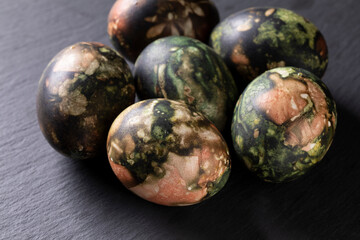 Painted Easter eggs. Easter composition - several eggs traditionally colored with natural, various plants dyes on a black stone background.