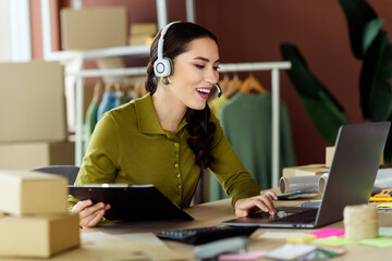 Young female entrepreneur in modern atelier working on laptop while managing tasks in stylish...