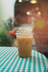 Coffee in cafe. Refreshing Iced Coffee in a Clear Cup on a Checkered Tablecloth in a Cozy Cafe Setting