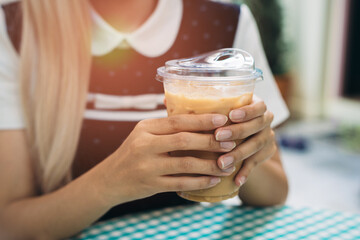 Hand holding coffee. Hands Holding Iced Coffee Drink in a Clear Plastic Cup on a Colorful Table...