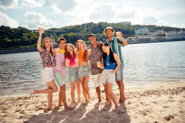 Buddies enjoying a sunny day at the beach with drinks, celebrating and creating joyful summer...