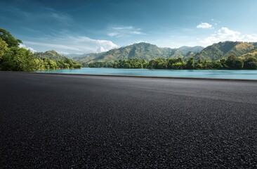 Fototapeta premium Asphalt track by a river with mountains and trees
