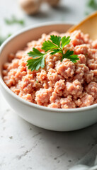 Fresh ground chicken in white bowl garnished with parsley on marble kitchen counter
