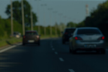 A somewhat unclear and blurry image depicts several cars driving swiftly along a major highway,...