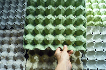 Environmental sustainability and packaging reuse concept: person holding paper-based egg tray made...