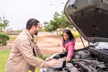 Couple checking car engine after breakdown on road trip
