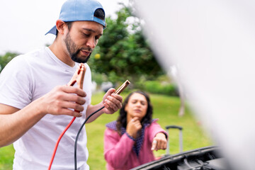 Mechanic holding jumper cables helping woman with car trouble