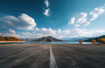 Empty asphalt runway leading to distant mountains under a partly cloudy sky