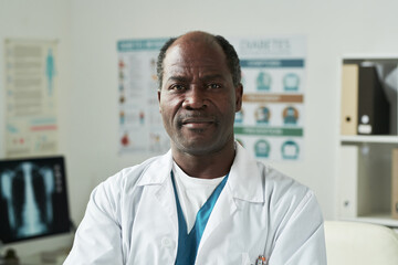 Portrait of middle aged Black man wearing medical coat standing in medical office, looking at...