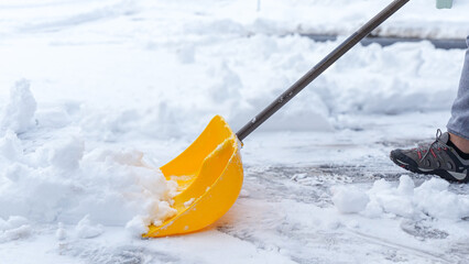 Man shoveling snow off of his driveway after a winter storm in Canada. Man with snow shovel cleans...
