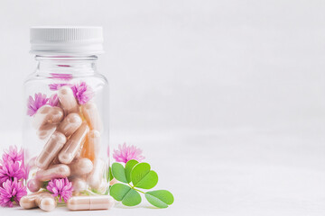 Transparent bottle with pink clover flowers and natural supplement phytoestrogen pills for restoring women hormonal balance. Menopause concept