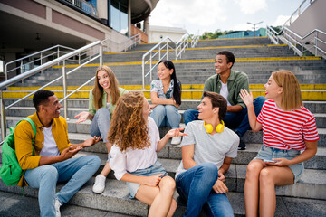 Young friends enjoying outdoor leisure time together on steps of urban building in casual attire