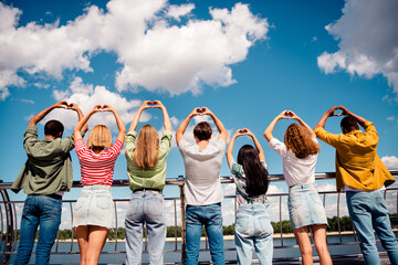 Obraz na płótnie Canvas Group of young friends outdoors showing heart gestures on a sunny day, celebrating friendship and unity together