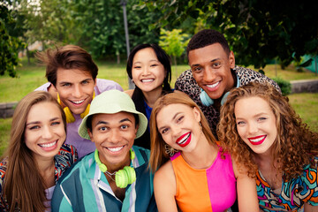 Diverse group of young friends enjoying a joyful day outdoors in summer, laughing and bonding in a...