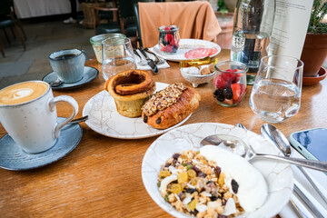 Continental breakfast on a table. Simple choice of pastries, yoghurt, cereals, toast with jam and butter, fruits. With coffees and juices. Breakfast for two at the table