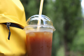 Coffee with juice in a disposable plastic cup with a straw. Coffee with orange juice, syrup and...
