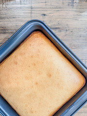Square, baked, yellow cake in a non-stick pan without icing