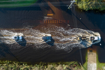 Hurricane flooded street with moving cars and surrounded with water houses in Florida residential...