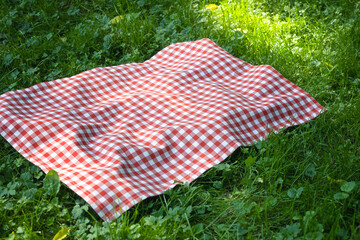 Red picnic checkered towel plaid on grass, food advertisement blank. Tabletop.Country cloth.Tablecloth outdoors.