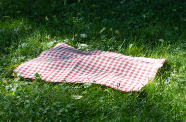 Red picnic tablecloth,cloth, checkered towel on green grass empty space.