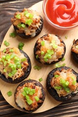 Delicious stuffed mushrooms and sauce on wooden table, top view