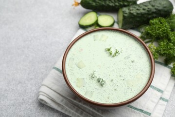 Tasty cucumber soup and ingredients on light grey table, closeup