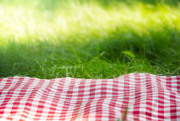 Red picnic checkered towel plaid on grass, empty space food advertisement summer design background, template.