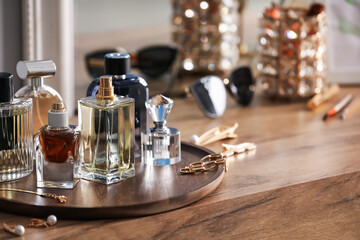 Bottles of different perfumes and accessories on wooden table, closeup. Space for text