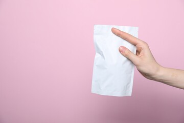 Woman with zipper stand-up pouch on pink background, closeup. Mockup for design