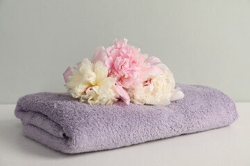 Soft towel and peony flowers on light grey background, closeup