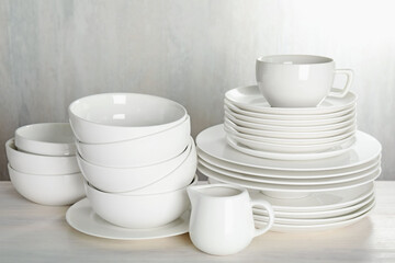 Different clean dishware on light wooden table indoors