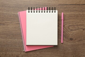 Notebooks and pen on wooden table, flat lay