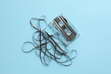 One audio cassette with magnetic tape on light blue background, top view