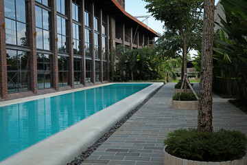 Outdoor swimming pool and green plants near building at luxury resort