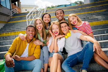 Happy group of diverse friends enjoying time together outdoors on city stairs during a sunny day in casual style