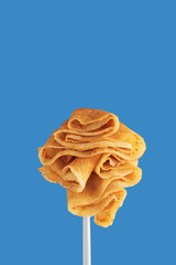 Golden pancakes on a fork against a vibrant blue background.