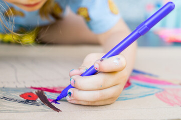 Boy drawing with markers on a piece of cardboard on the floor