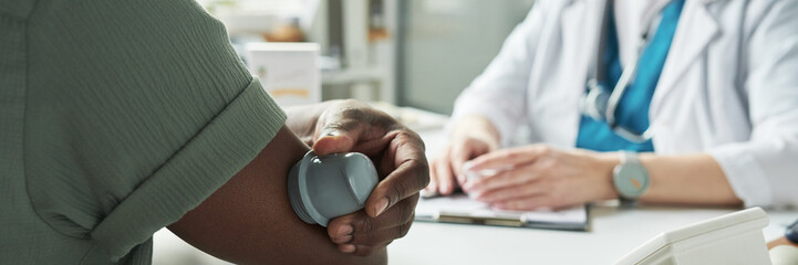 Middle aged Black man having blood pressure measured by medical professional during diabetes...